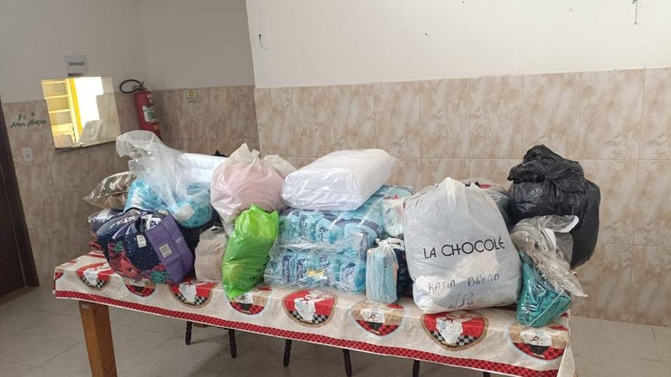 Mesa coberta de pacotes de fraldas e doações